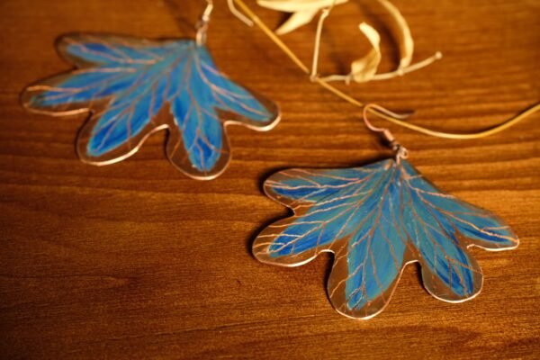 Pendientes elaborados de manera artesanal pintados a mano de hojas con tonos azules inspirados en un Bosque encantado de la flora Colombiana material cobre