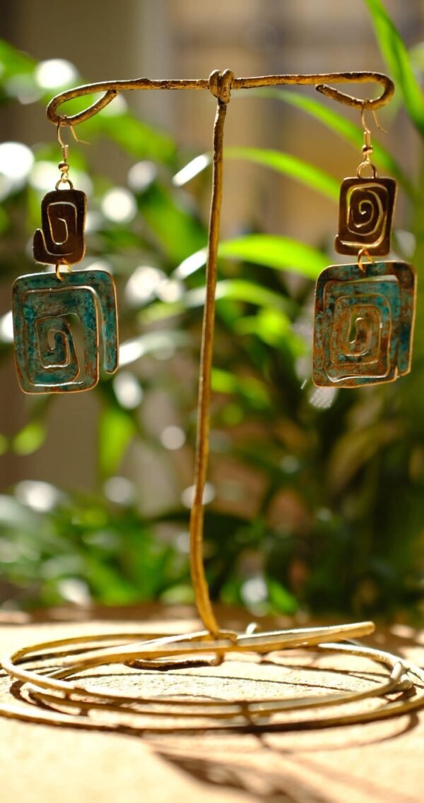 Pendientes/Aretes inspirados en la simbología Wayuu del pueblo aborigen Colombiano. Aretes elaborados de manera artesanal patinados bajo la reacción natural del metal y el ambiente, complementados con sutiles trazos de pintura manual. Material Latón con pasantes chapados en oro de 18 Kt de 1,2 mm. Medidas aproximadas: 7,05 cm altura total. Ancho de figura pequeña 2 cm y de figura grande 3 cm. El color de los pendientes en la parte de patinada es azul turquesa. Dependiendo el ángulo y la luz de donde los estes viendo, puede verse con un tono un poco más azul celeste. La simbología de estos pendientes representan purificación, protección de la verdad y eternidad.