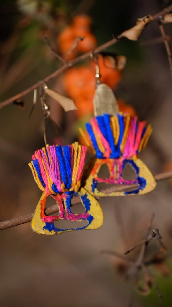 Pendientes artesanales pintados a mano con rostro de figura aborigen con hilos de colores.