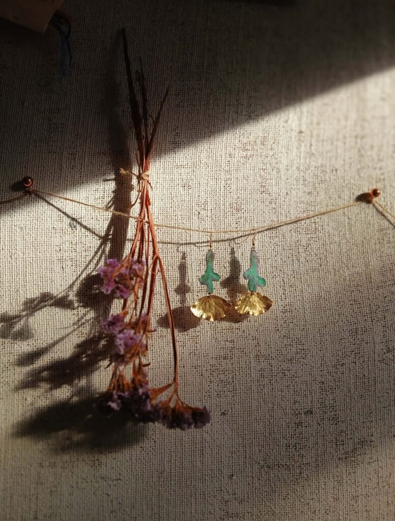 Pieza de joyería artesanal Flores en Reposo, pintada a mano con pigmentos artísticos y trazos finos, inspirada en la biodiversidad andina y la feminidad empoderada.