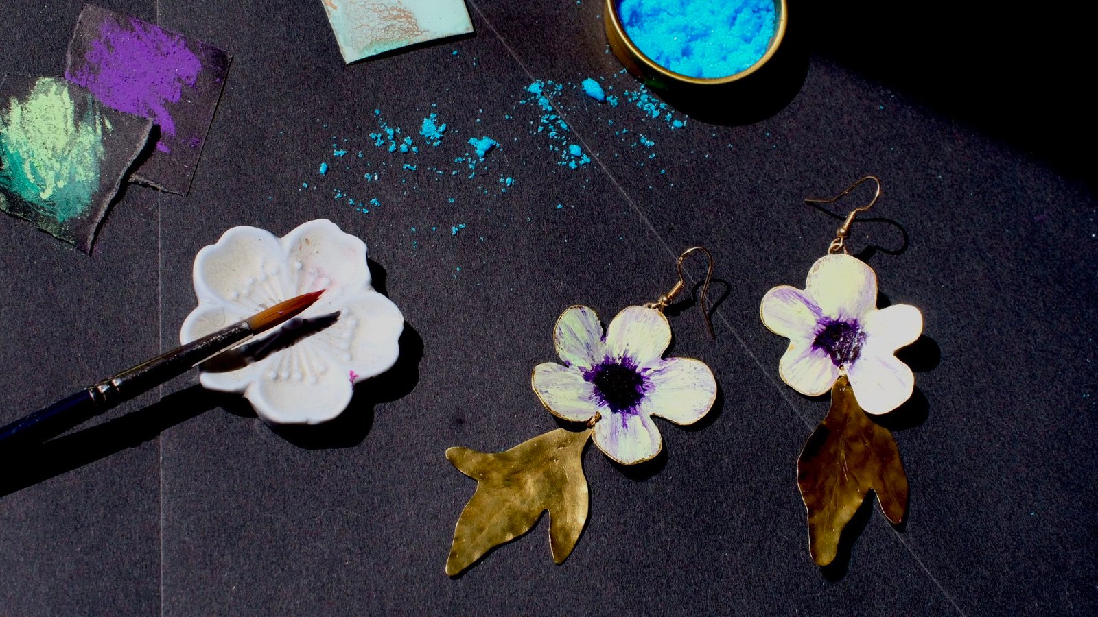 Pendientes de flores de manzana verde hechos a mano y pintados con pigmentos artísticos, con tallos bañados en oro de la colección Noa de Andina by Angélica.